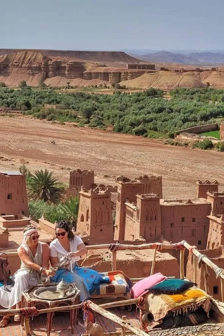 Ait Ben Haddou kasbah and palm trees seen across the dry river bed