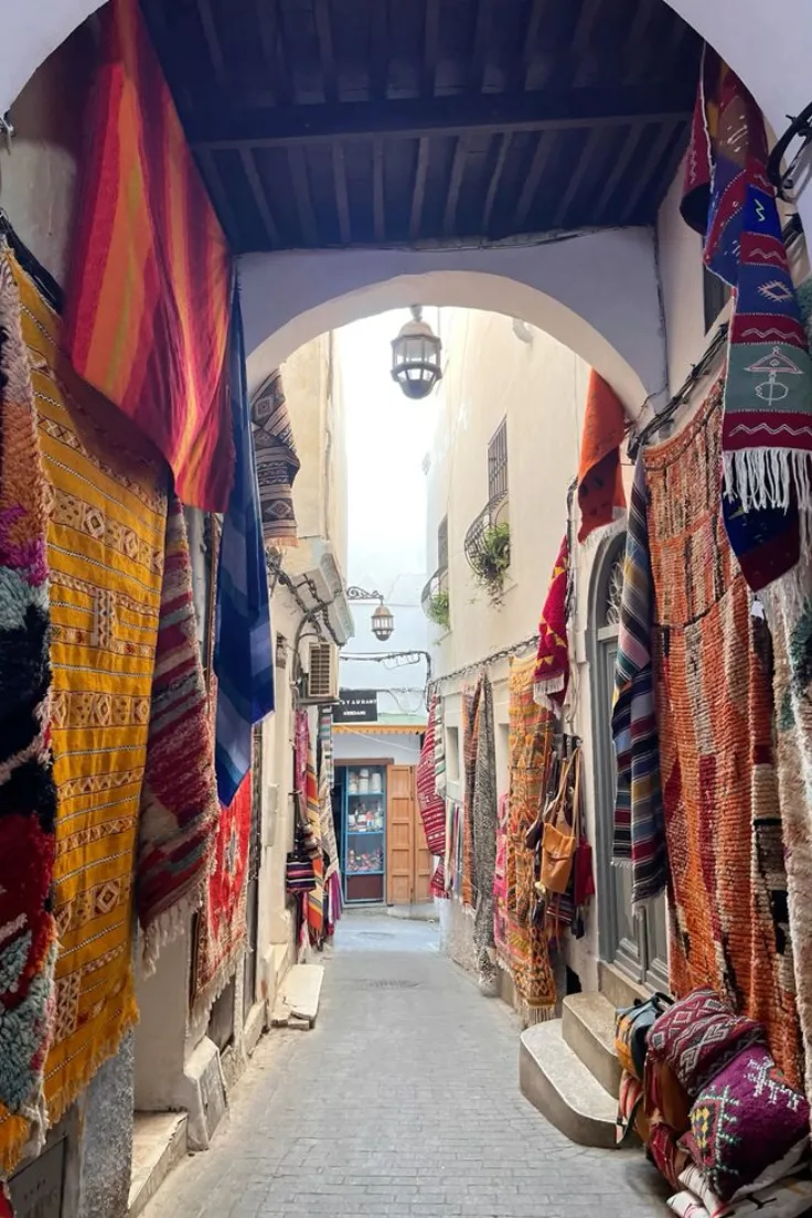 Colorful carpets and textiles hanging in a narrow Tangier medina street