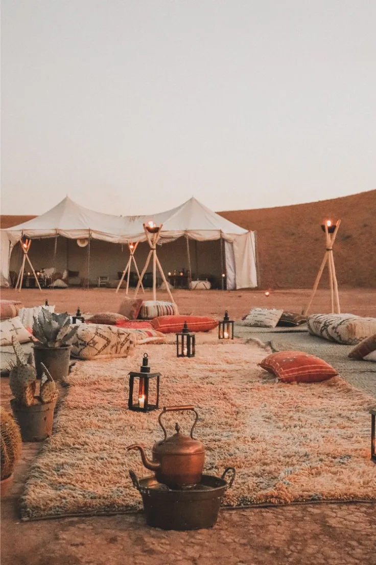 Zagora desert camp exterior Desert camp lounge with white tents, cushions and torches in the Zagora desert