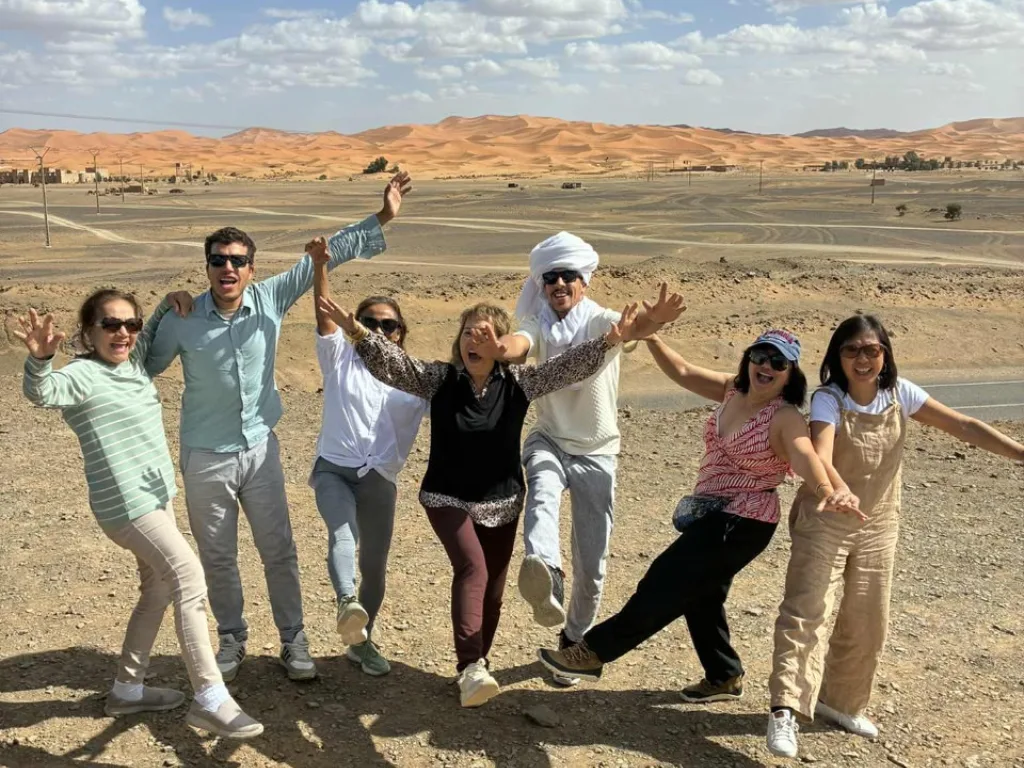 Group of travelers celebrating in the Moroccan desert near Merzouga