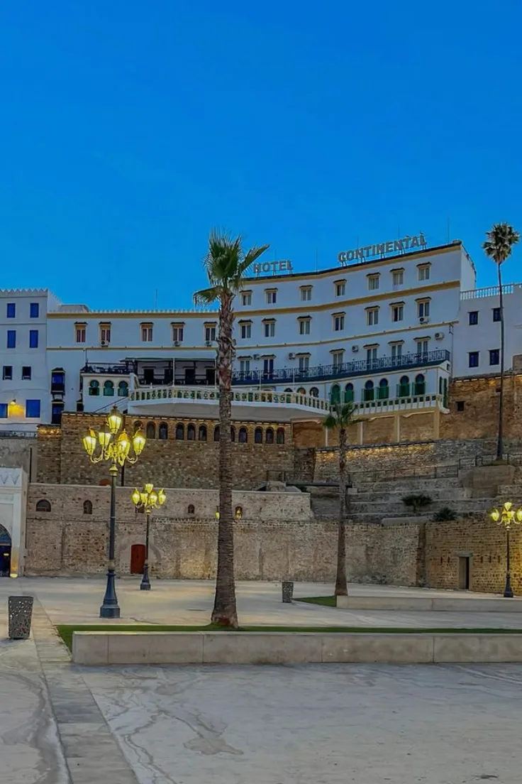 Historic building facade with a palm tree and street lamps at Petit Socco in Tangier