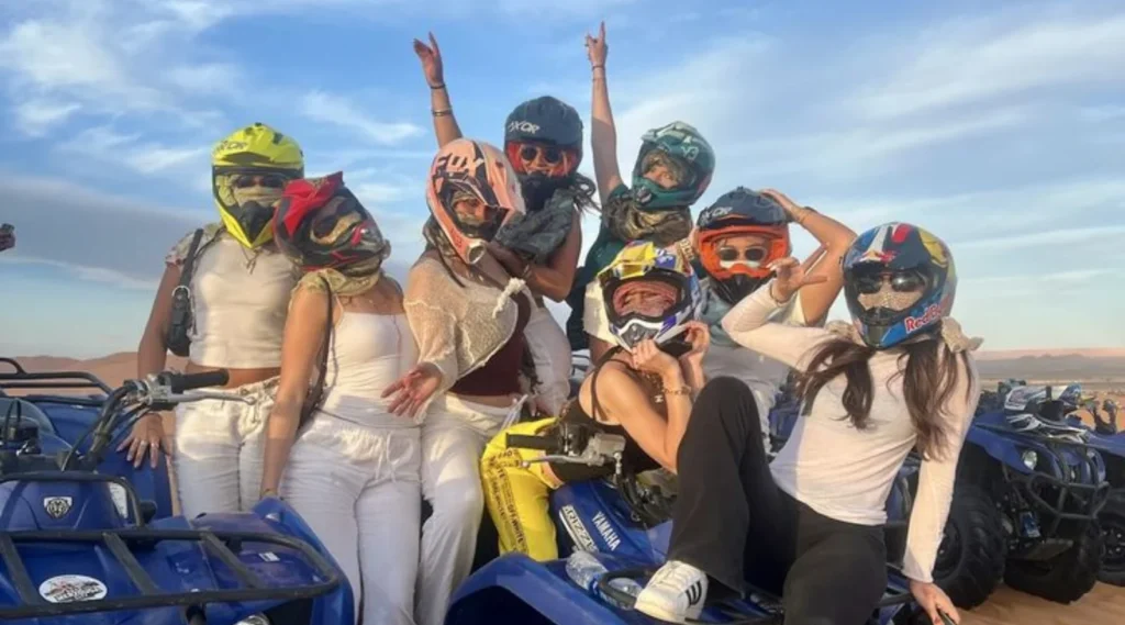 Group of travelers in helmets posing on quad bikes in the dunes during a quad marrakech tour