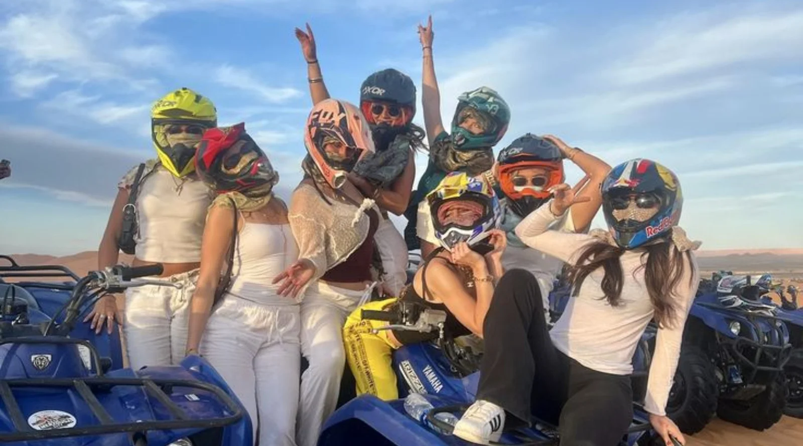 Group of travelers in helmets posing on quad bikes in the dunes during a quad marrakech tour