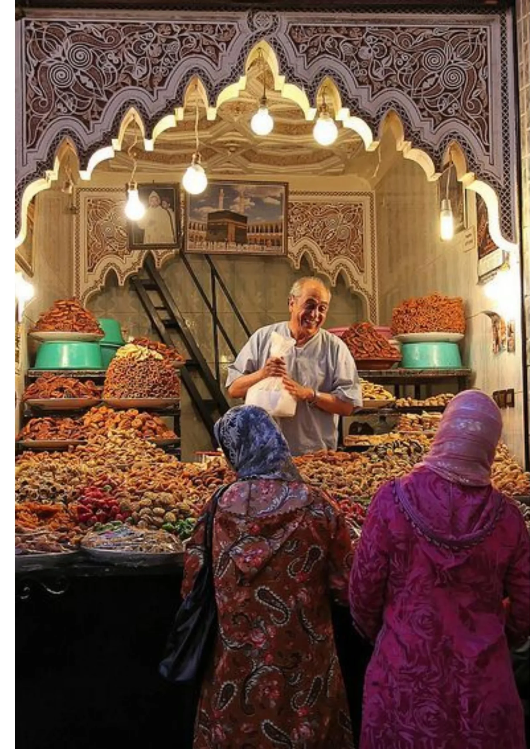 Spice merchant among colorful dried fruit and spice displays in the Fes medina
