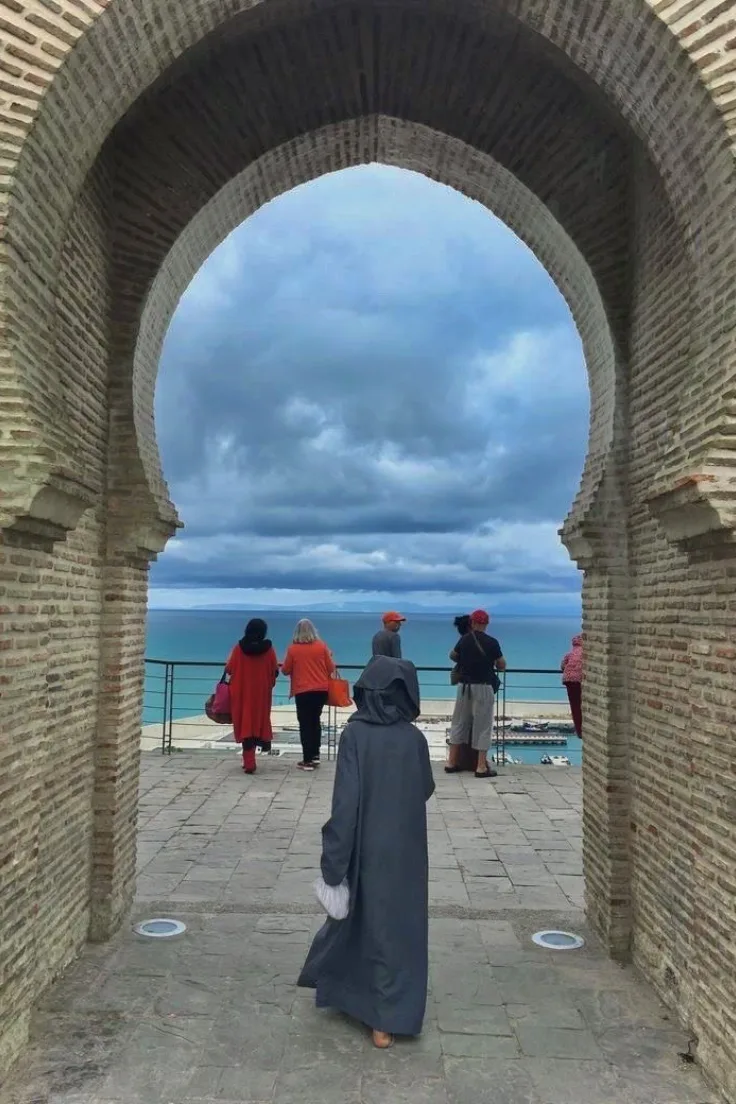 Visitors looking out to sea through a brick archway in Tangier